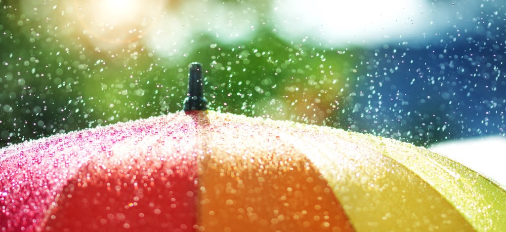 Rain drops falling onto umbrella with rainbow colour